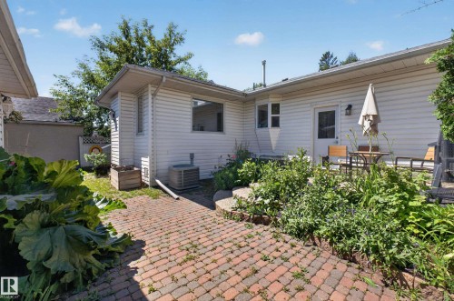 Outdoor patio with brick paver flooring, surrounded by established garden beds - 11015 122 Street, Edmonton, AB 