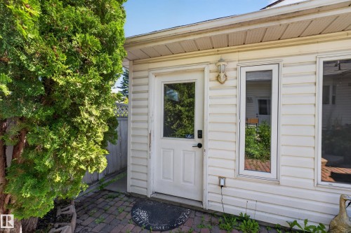 Exterior siding with white trim, a glass-paneled door, and an exterior wall light fixture - 11015 122 Street, Edmonton, AB 