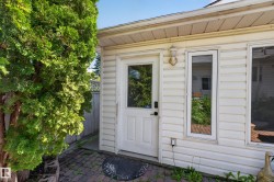 Exterior siding with white trim, a glass-paneled door, and an exterior wall light fixture - 