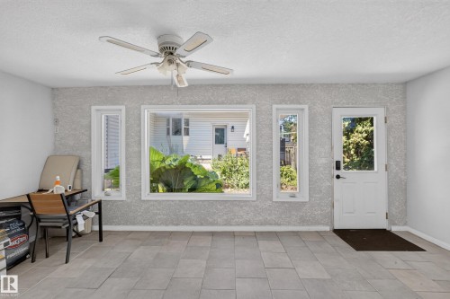 Sunroom featuring light-toned tile flooring, textured wall finish, and a ceiling fan - 11015 122 Street, Edmonton, AB 