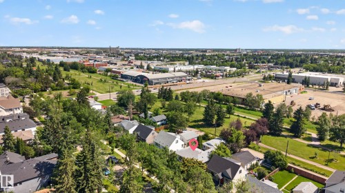 Aerial perspective showcasing a residential property with a light-colored roof, surrounded by mature trees - 11015 122 Street, Edmonton, AB 