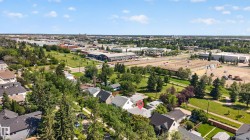Aerial perspective showcasing a residential property with a light-colored roof, surrounded by mature trees - 