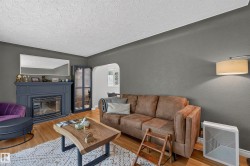Living area featuring wood-finish flooring, a painted fireplace with mantel, and a built-in display cabinet - 