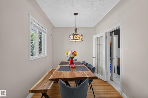 Bright room featuring wood-finish flooring, a white-framed window, a decorative ceiling light fixture, and French doors with glass panes - 11015 122 Street, Edmonton, AB 