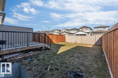Expansive backyard featuring a wood deck with black railings, a full privacy fence, and a generous grass area - 1715 27 Street, Edmonton, AB 