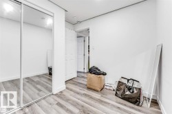 Room featuring wood-finish flooring, white walls, and a large mirrored sliding closet door - 