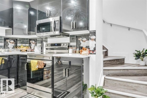 Kitchen featuring glossy black cabinetry, stainless steel appliances, a tile backsplash, and light-toned countertops - 1715 27 Street, Edmonton, AB 
