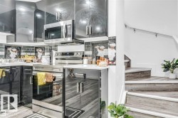 Kitchen featuring glossy black cabinetry, stainless steel appliances, a tile backsplash, and light-toned countertops - 