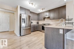 Contemporary kitchen featuring wood-finish flooring, dark wood-finish cabinetry, stainless steel appliances, a light-toned countertop, and a subway tile backsplash - 