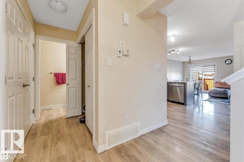 Entryway featuring wood-finish flooring, two white panel doors, and a partial view of the kitchen and dining area - 1715 27 Street, Edmonton, AB 