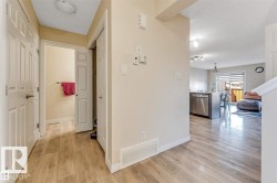 Entryway featuring wood-finish flooring, two white panel doors, and a partial view of the kitchen and dining area - 