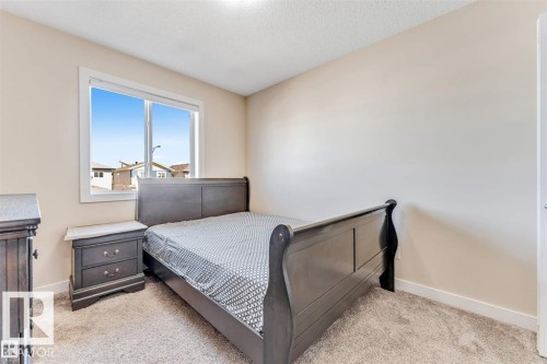 Carpeted bedroom featuring neutral-toned walls, a white trim window, and white baseboards - 1715 27 Street, Edmonton, AB 