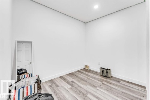 Spacious room featuring light wood-finish flooring, crisp white walls, and recessed lighting - 1715 27 Street, Edmonton, AB 