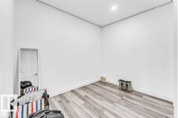 Spacious room featuring light wood-finish flooring, crisp white walls, and recessed lighting - 