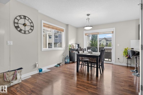Wood-finish flooring throughout, featuring a window with natural light, a sliding glass door providing exterior access, recessed lighting, and a contemporary ceiling fixture - 89 9535 217 Street, Edmonton, AB 