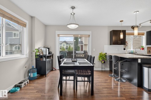 Open concept living space featuring wood-finish flooring, a contemporary dining area, and a kitchen island with seating - 89 9535 217 Street, Edmonton, AB 