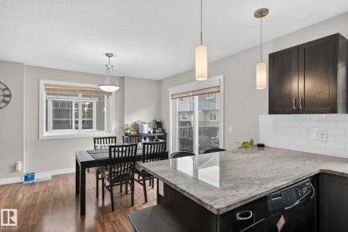Kitchen with dark wood-finish cabinetry, light-toned countertops, and white subway tile backsplash - 89 9535 217 Street, Edmonton, AB 