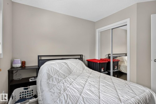 Bedroom featuring light neutral wall tones, white trim, and a double mirrored closet - 89 9535 217 Street, Edmonton, AB 