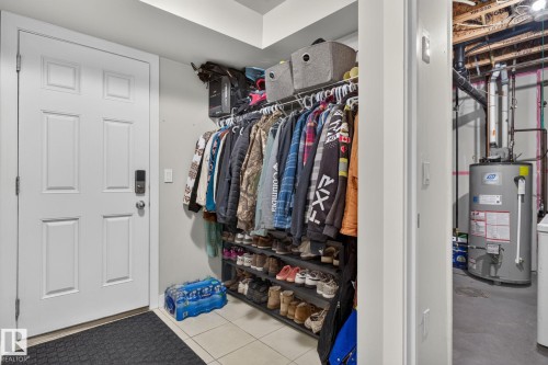 Entryway featuring a six-panel door with smart lock hardware, tiled flooring, and an open storage system - 89 9535 217 Street, Edmonton, AB 
