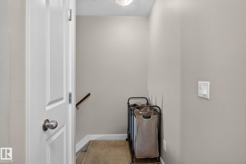 Staircase featuring wood-finish handrail, carpeted treads, and painted walls - 89 9535 217 Street, Edmonton, AB 