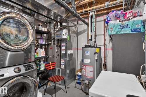 Dedicated utility area featuring a stacked washer and dryer, water heater, and furnace - 89 9535 217 Street, Edmonton, AB 
