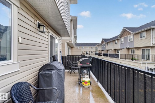 Private balcony featuring light-colored siding, a black metal railing, and a concrete surface - 89 9535 217 Street, Edmonton, AB 