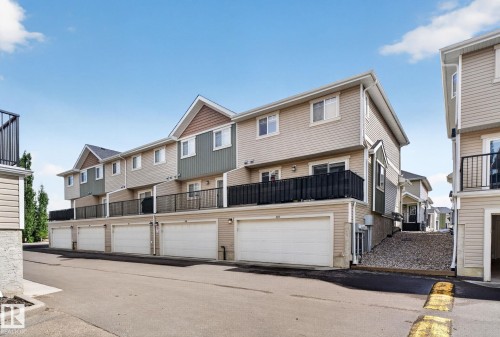 Row of multi-level townhomes featuring beige siding and contrasting green accent panels - 89 9535 217 Street, Edmonton, AB 