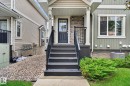 Front entry featuring a dark paneled door, stone facade accents, and a dark railing - 89 9535 217 Street, Edmonton, AB 