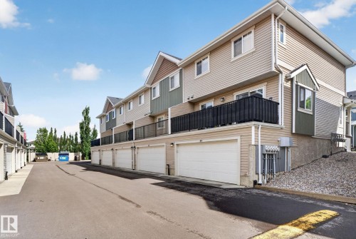 Multi-level townhome featuring a private balcony with black metal railing, attached single-car garage, and neutral vinyl siding - 89 9535 217 Street, Edmonton, AB 