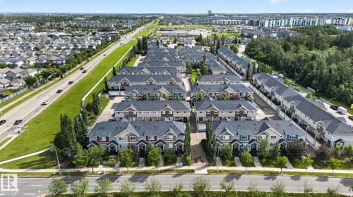 Residential development featuring multiple rows of multi-story townhomes with dark shingle roofs, varied exterior siding, and individual front entrances - 89 9535 217 Street, Edmonton, AB 