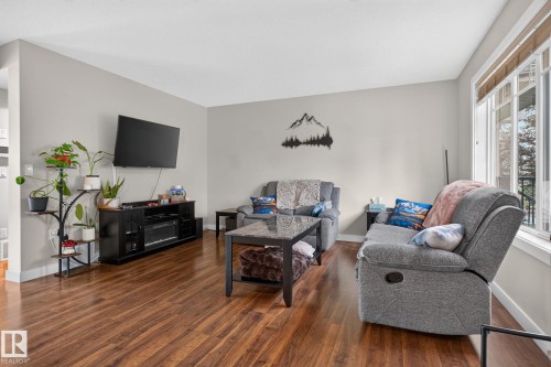 Living area featuring wood-finish flooring, light gray wall tones, and substantial window with blinds - 89 9535 217 Street, Edmonton, AB 