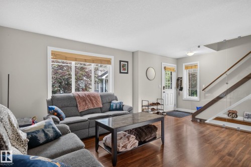 Bright living space featuring wood-finish flooring and a contemporary staircase with glass railing - 89 9535 217 Street, Edmonton, AB 