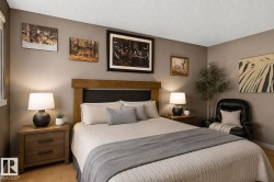 Wood-finish flooring anchors this space featuring a prominent wooden headboard, dual bedside tables with integrated storage, and matching table lamps - 