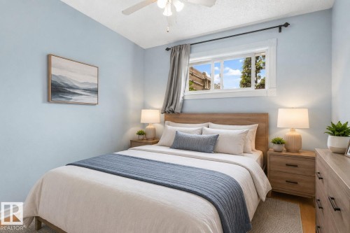 Bedroom featuring a natural wood-finish bed frame, light blue wall paint, and wood-finish flooring - 8316 157 Avenue, Edmonton, AB 