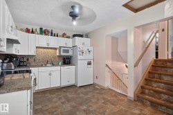 Kitchen featuring white cabinetry, stone-look countertops, and a mosaic tile backsplash - 