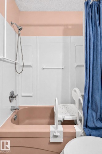 Bathtub with chrome fixtures, showerhead with flexible hose, and wall-mounted white paneling - 8316 157 Avenue, Edmonton, AB 
