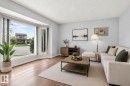 Living area featuring a large bay window, wood-finish flooring, light-toned wall paint, and textured ceiling - 8316 157 Avenue, Edmonton, AB 