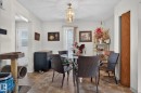 Dining area featuring a contemporary chandelier, textured ceiling, and wood-finish flooring - 8316 157 Avenue, Edmonton, AB 