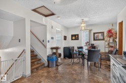 Dining area featuring a glass-top table, LVP flooring, and a decorative light fixture - 