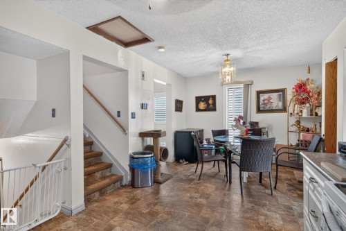 Dining area featuring a glass-top table, LVP flooring, and a decorative light fixture - 8316 157 Avenue, Edmonton, AB 
