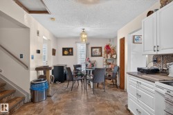 Open concept living area featuring wood-finish flooring, white cabinetry, and a mosaic tile backsplash - 