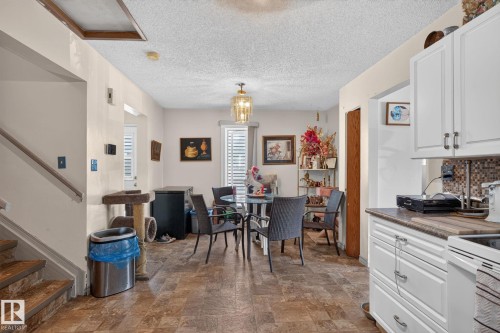 Open concept living area featuring wood-finish flooring, white cabinetry, and a mosaic tile backsplash - 8316 157 Avenue, Edmonton, AB 