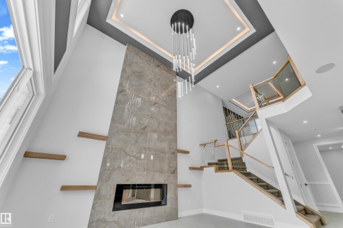 Two-story living area featuring a dramatic fireplace with a linear insert and stone-finish surround - 2611 62 Avenue, Rural Leduc County, AB - Indoor Photo Showing Other Room With Fireplace