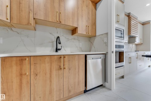Kitchen featuring wood-finish cabinetry with gold-tone hardware, white countertops, and a white marble-look tile backsplash - 2611 62 Avenue, Rural Leduc County, AB - Indoor Photo Showing Kitchen