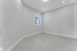 Spacious room featuring light gray walls, large format tile flooring, a window with white trim, a flush mount ceiling light, and recessed lighting - 
