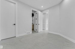 Spacious room featuring large format tile flooring, contemporary baseboards, and bright white walls - 