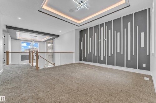 Lounge area featuring a unique accent wall with vertical paneling, tray ceiling with ambient lighting, and modern chandelier - 2611 62 Avenue, Rural Leduc County, AB - Indoor Photo Showing Other Room