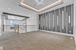 Lounge area featuring a unique accent wall with vertical paneling, tray ceiling with ambient lighting, and modern chandelier - 