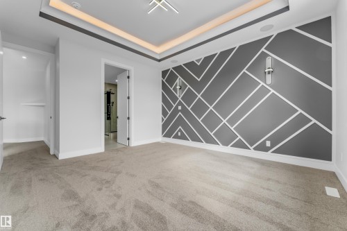 Contemporary room featuring a decorative accent wall with geometric molding, recessed ceiling lighting, a modern overhead light fixture, and two wall-mounted sconces - 2611 62 Avenue, Rural Leduc County, AB - Indoor Photo Showing Other Room