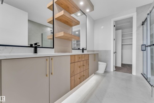 Contemporary bathroom vanity featuring dual sinks, a stone-finish countertop, and integrated shelving - 2611 62 Avenue, Rural Leduc County, AB - Indoor